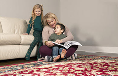 woman sitting in front of couch with children on oriental rug