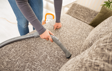 person vacuuming sofa