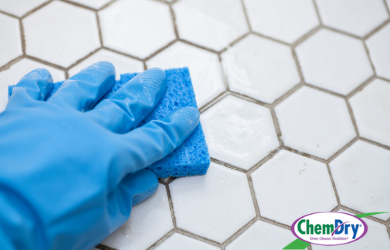 Blue glove cleaning white tile and grout
