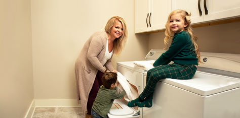 Mom and son unload dryer while daughter sits on washing machine