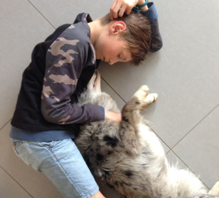 boy and dog laying on grey tile floor