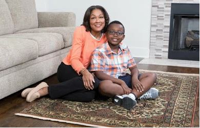 Mother and son sitting on an area rug in front of a couch