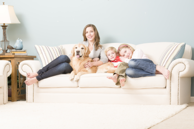 Mother relaxing with her 2 children and dog on a couch