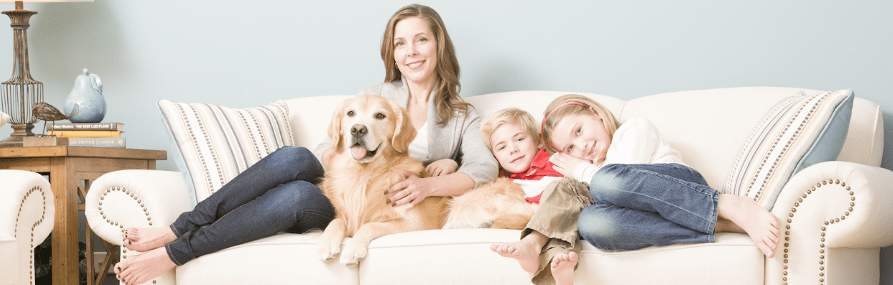 Mom with her 2 children and dog relaxing on a couch