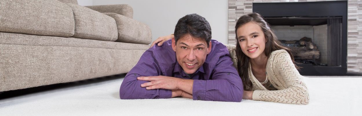 Father and daughter relaxing on white carpet in living room