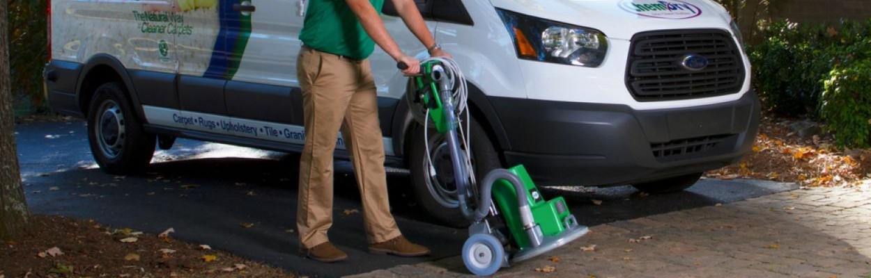 Chem-Dry employee transporting carpet cleaning equipment into a business
