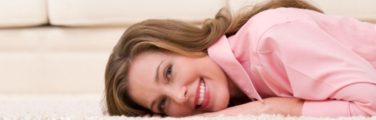 Smiling woman laying down on a white shag carpet