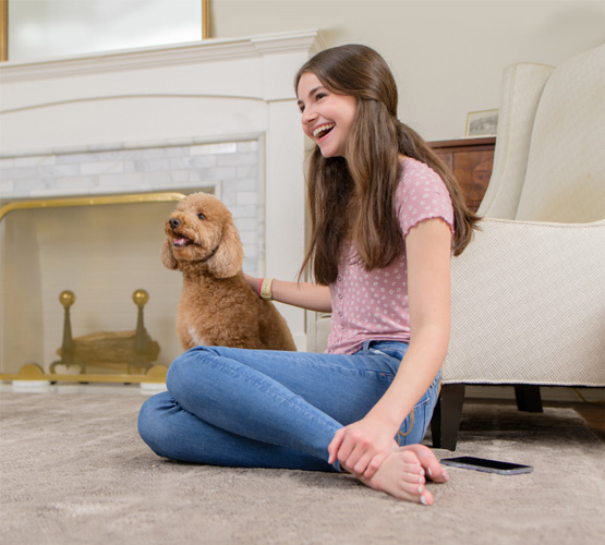 Girl sitting on carpet next to dog