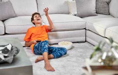 teenage boy enjoys snack while sitting on clean carpet