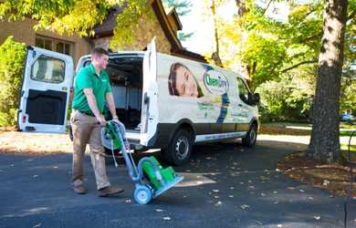 Professional carpet cleaning tech moves equipment into a home