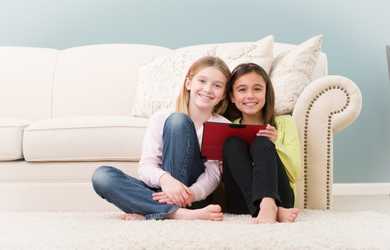 two young girls read a book on carpet cleaned by Chem-Dry