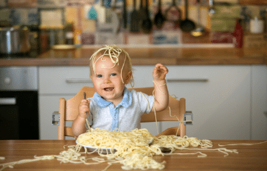 messy toddler covered in pasta